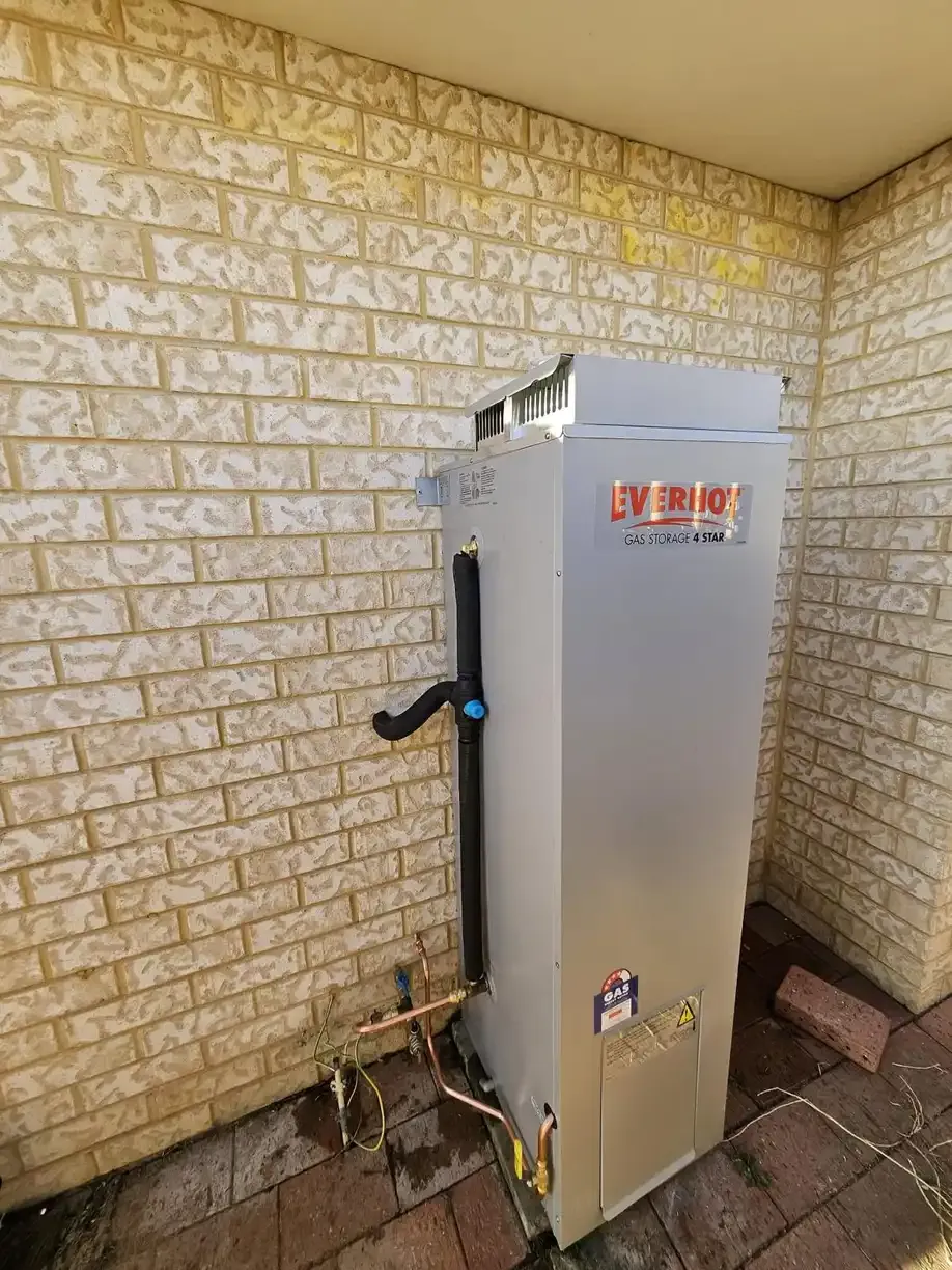 A newly installed gas storage hot water unit with its flue and gas connection.
