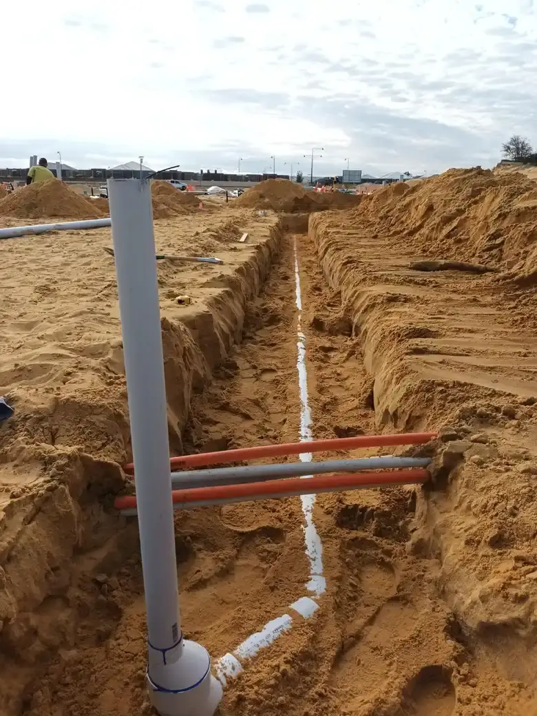 A pre-slab waste riser and drain run on a building site.